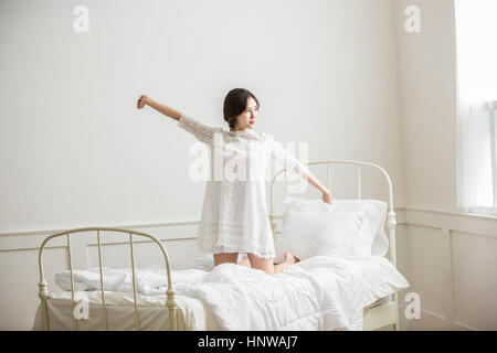 Giovane donna stretching nel letto Foto Stock