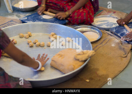 Donne che fanno indiano piatto pane, chiamato chapati, su un grande piatto d'argento. Foto Stock