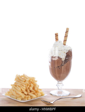Gelato al cioccolato in tazza di vetro con la panna montata e la piazza piastra bianca di una pila di patatine fritte su un legno chiaro tavolo. Fad di cibo o di nuova tendenza. Foto Stock