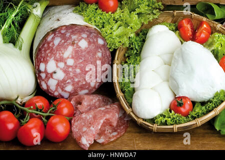 Salame Toscano, mozzarella di bufala campana con insalata, finocchio, pomodori nella composizione di legno pannelli di taglio Foto Stock