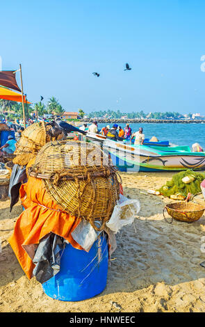 NEGOMBO, SRI LANKA - Novembre 25, 2016: l'asciugatura cesti invertito presso la spiaggia di sabbia del porto di pescatori con le barche dei pescatori e sullo sfondo, Foto Stock