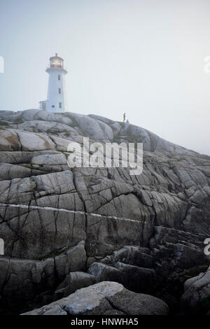 Giovane sulle rocce da faro, Peggy's Cove, Nova Scotia, Canada Foto Stock