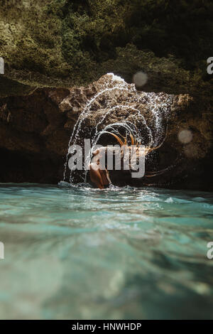 La donna nel water filled cave gettando indietro i capelli umidi, schizzi, Oahu, Hawaii, STATI UNITI D'AMERICA Foto Stock