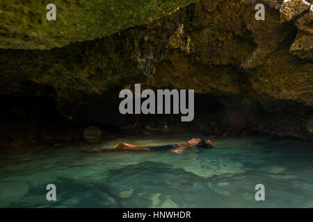 Donna fluttuante nel water filled cave, Oahu, Hawaii, STATI UNITI D'AMERICA Foto Stock