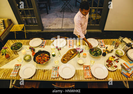 L'uomo immissione piatto sul tavolo da pranzo Foto Stock