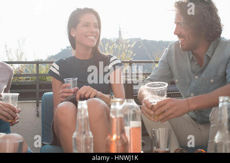 Giovani amici adulti di rilassarsi con un drink in terrazza sul tetto delle parti Foto Stock