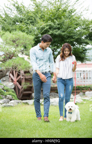 Giovane coppia sorridente walking cane Foto Stock