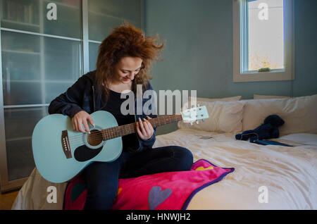 Adolescente a suonare la chitarra in camera da letto Foto Stock