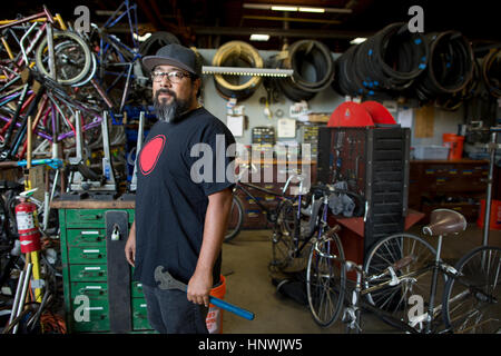 Ritratto di uomo maturo tenendo la chiave in officina biciclette Foto Stock