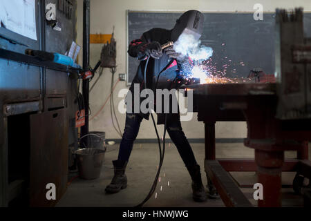 Femmina lavoratore in metallo la saldatura al banco di lavoro in aula Foto Stock