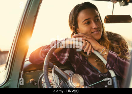 Giovane donna appoggiata contro il volante in pickup truck a Newport Beach, California, Stati Uniti d'America Foto Stock