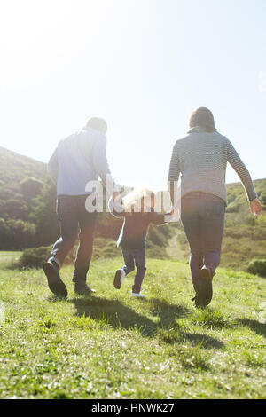 Vista posteriore della metà adulto giovane e figlia passeggiando nel campo Foto Stock