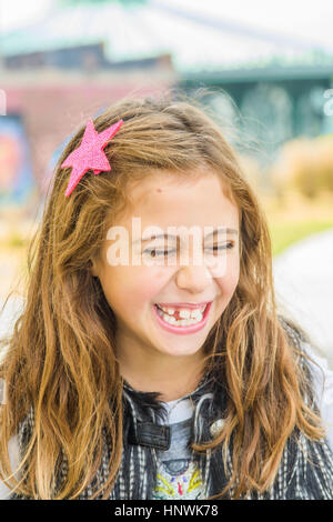 Ritratto di ragazza con lunghi marrone capelli ondulati ridere Foto Stock