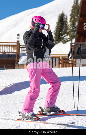 Sciatore femmina di vestirsi nella parte anteriore dello sci hut Foto Stock