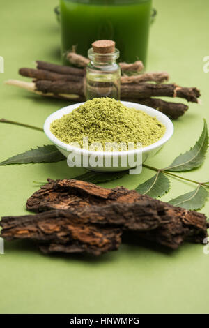 Ayurvedico medicinali Azadirachta indica o Neem foglie in mortaio e pestello con neem pasta, succo di frutta e ramoscelli, polvere e olio, il fuoco selettivo Foto Stock