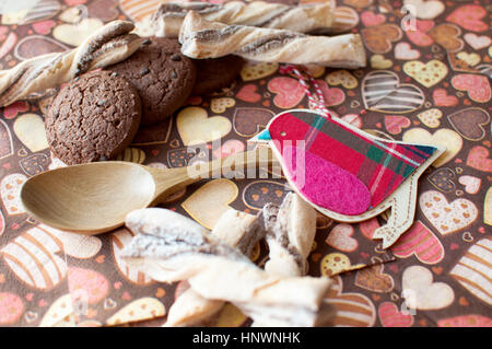 Rosso uccello giocattolo e cookie sul tovagliolo scuro con immagine di heartsclose fino. Messa a fuoco selettiva. Foto Stock