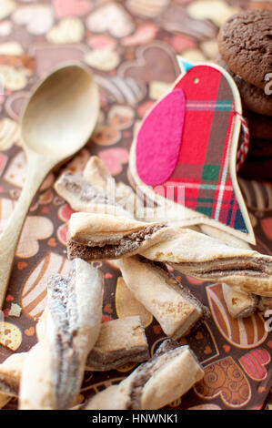 Rosso uccello giocattolo e cookie sul tovagliolo scuro con immagine di heartsclose fino. Messa a fuoco selettiva. Foto Stock