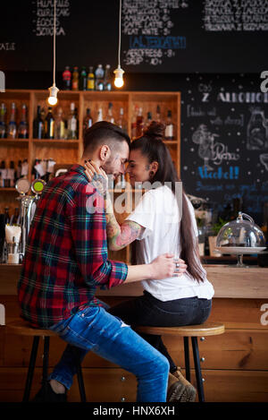 Giovane su sgabelli in coffee shop faccia a faccia sorridente Foto Stock