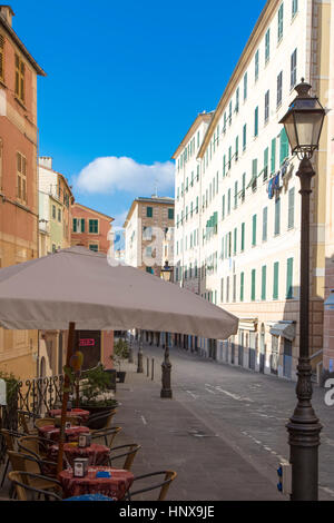 La caffetteria all'aperto con tavoli e ombrelloni in una stradina nel resort villaggio di pescatori di Camogli sulla Riviera Italiana, una popolare destinazione turistica Foto Stock