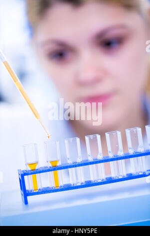 Un giovane farmacista azienda provetta con del liquido durante l'esperimento di chimica. Assistente di laboratorio con la pipetta ricerca del cancro delle cellule staminali. Femmina Foto Stock