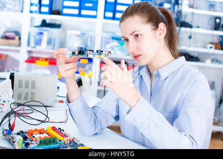 Ingegnere di lavoro con i circuiti. Una donna ingegnere circuiti saldature seduti ad un tavolo. Microchip fabbrica di produzione. Il processo tecnologico. Assemblaggio Foto Stock