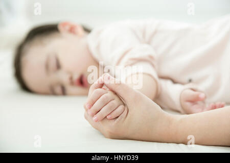Mano che tiene il bambino dorme la mano Foto Stock