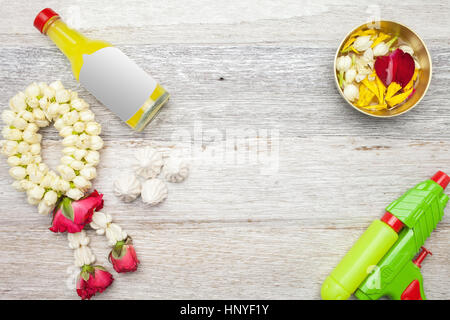 Songkran Festival : Profumo,ghirlanda floreale,,alimentazione e pistola sul bianco sullo sfondo di legno Foto Stock