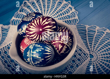 Gruppo di dipinti a mano le uova di pasqua sul blu superficie in legno Foto Stock