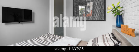Panorama di luminose e piccola camera da letto con letto matrimoniale e un muro di mattoni Foto Stock