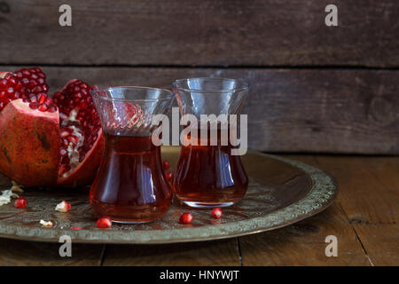 Un bicchieri di succo di melograno con freschi frutti di melograno su un tavolo di legno. Vitamine e minerali. Bibita salutare concetto. Foto Stock