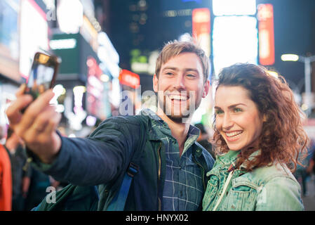 Coppia giovane tenendo selfie in Times Square a New York City, New York, Stati Uniti d'America Foto Stock