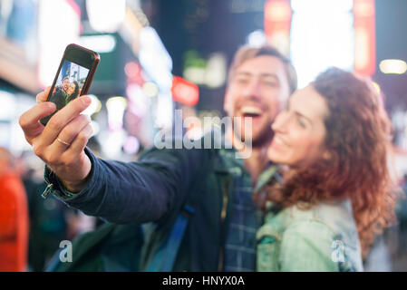 Coppia giovane tenendo selfie in Times Square a New York City, New York, Stati Uniti d'America Foto Stock
