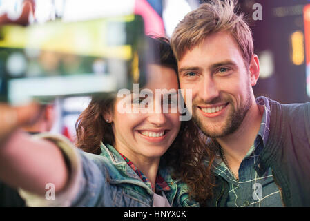 Coppia giovane tenendo selfie in città illuminata street Foto Stock