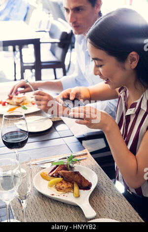 Donna che utilizza smartphone a fotografare il suo pasto in ristorante Foto Stock