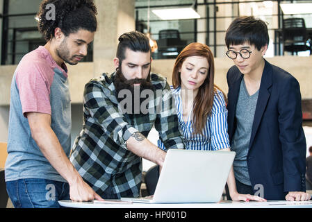 I colleghi che lavorano insieme con il computer portatile Foto Stock