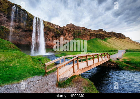 Cascata Seljalandfoss al tramonto. Ponte sul fiume. Fantas Foto Stock