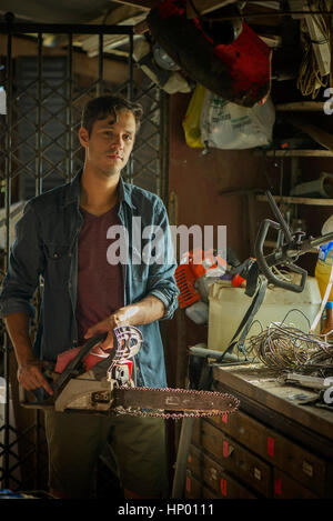 Uomo in sala archiviazione tenendo chainsaw Foto Stock