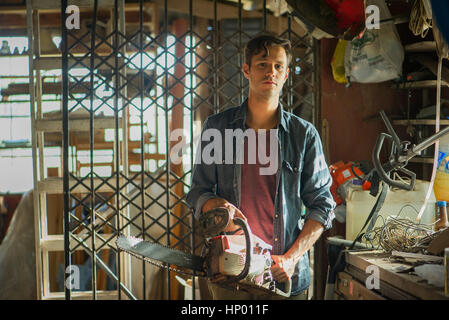 Uomo con chainsaw in officina, ritratto Foto Stock