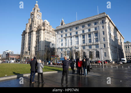 I turisti di scattare le foto con i Beatles statua che si trova nella parte anteriore del Pier Head palazzi Liverpool Regno Unito Foto Stock