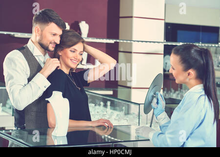 Giovane uomo aiutando la sua fidanzata con raccordo a collana in je Foto Stock