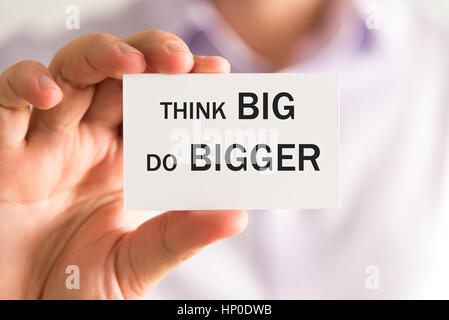 Primo piano su imprenditore tenendo una scheda con il testo pensa in grande fare grandi affari, concetto di immagine con messa a fuoco morbida dello sfondo Foto Stock