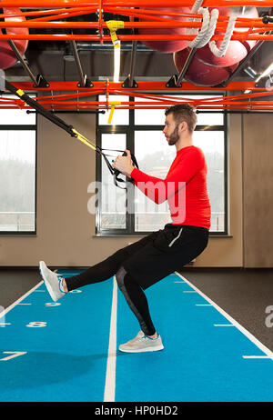 Ricci bianco barbuto uomo sportivo esercitando con cinghie di fitness in palestra Crossfit istruttore presso la palestra facendo Excersise. Uomo Fitness workout sugli anelli. Sport e fitness. Crossfit allenamento Foto Stock