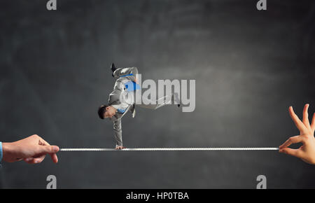 Giovane imprenditore allegro facendo handstand sulla corda tesa Foto Stock