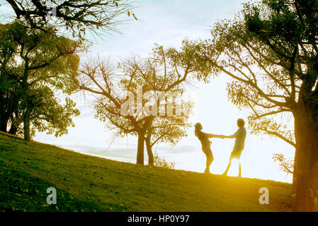 Giovane tenendo le mani in posizione di parcheggio, retroilluminato da luce solare Foto Stock