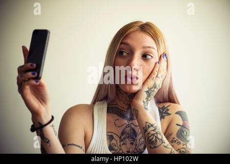 La donna tatuata tenendo selfie con lo smartphone Foto Stock