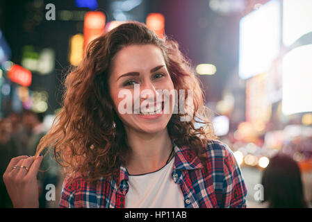 Giovane donna in piedi in città illuminata street Foto Stock