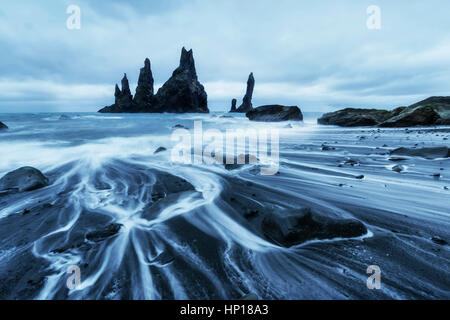 La Roccia Troll dita. Reynisdrangar scogliere. Spiaggia di sabbia nera Foto Stock