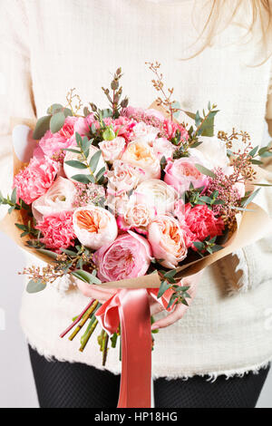 Raccolta di diverse varietà di giardino di rose, garofani e eucalipto. La ragazza mani colori delicato bouquet di fiori su fondo bianco. Foto Stock