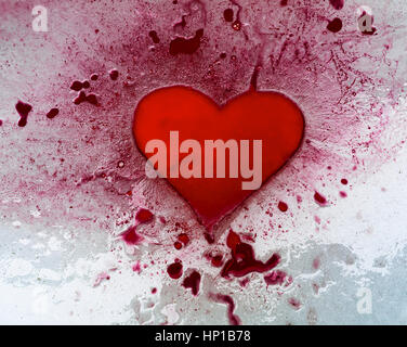 Inchiostro rosso cuore su ghiaccio. Rosso il pooling di inchiostro in una a forma di cuore, cava e tutta e in altre depressioni nella superficie del ghiaccio. Foto Stock