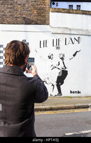 Islington, Londra, 17 feb 2017. I passanti da guardare a un nuovo graffiti da artista di strada Bambi che raffigura il presidente statunitense Donald Trump e British PM Theresa Maggio dancing in 'giacciono giacciono terreni", un riferimento per l'acclamato film "La La Terra". Il lavoro è apparso questa settimana su una strada laterale nel quartiere di Islington. Credito: Imageplotter News e sport/Alamy Live News Foto Stock